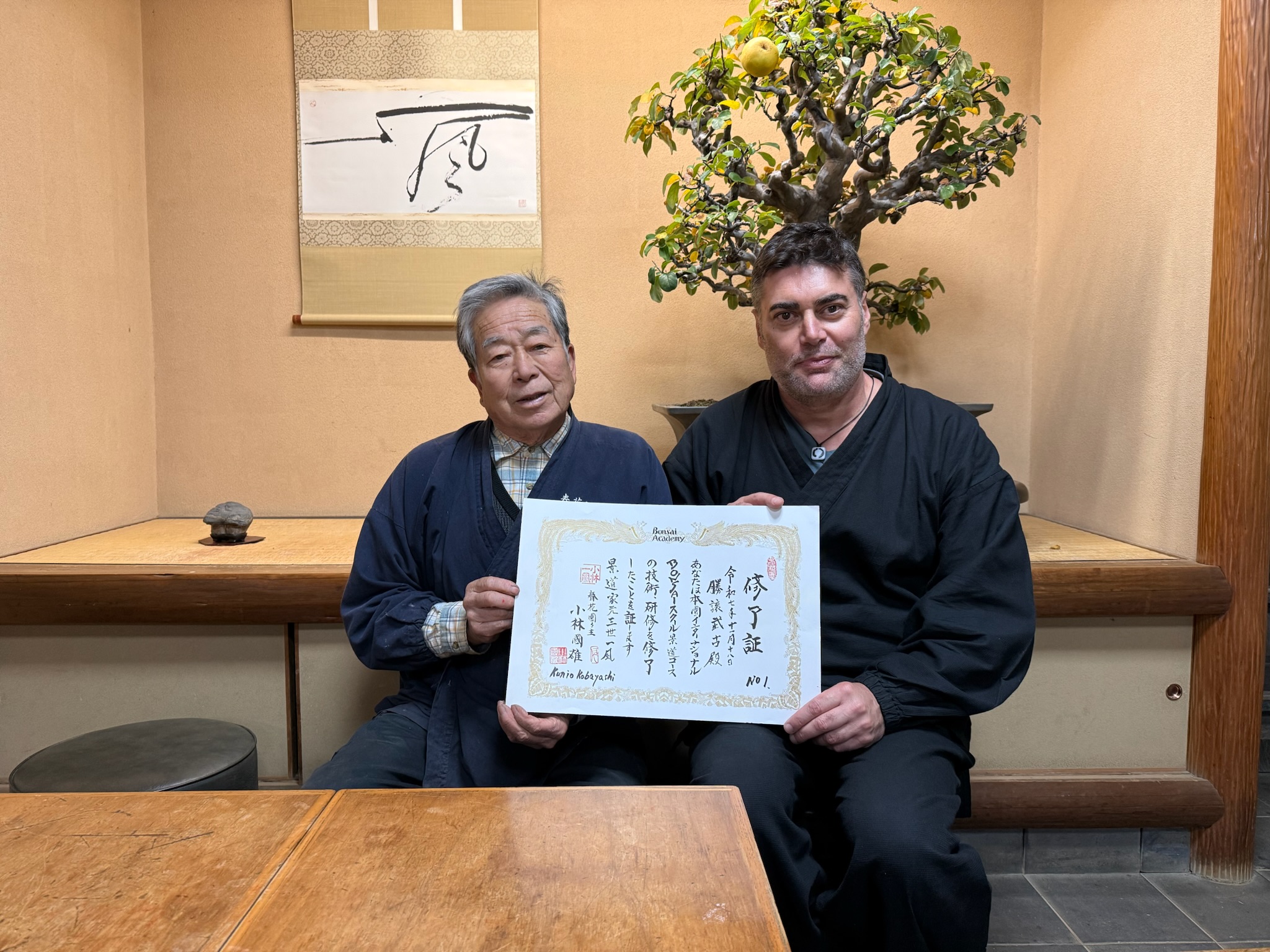 Marcial Yuste Blasco y Kobayashi Ippū sosteniendo el diploma N.º 1 en el Museo Shunkaen, ante un kakejiku con el carácter 風